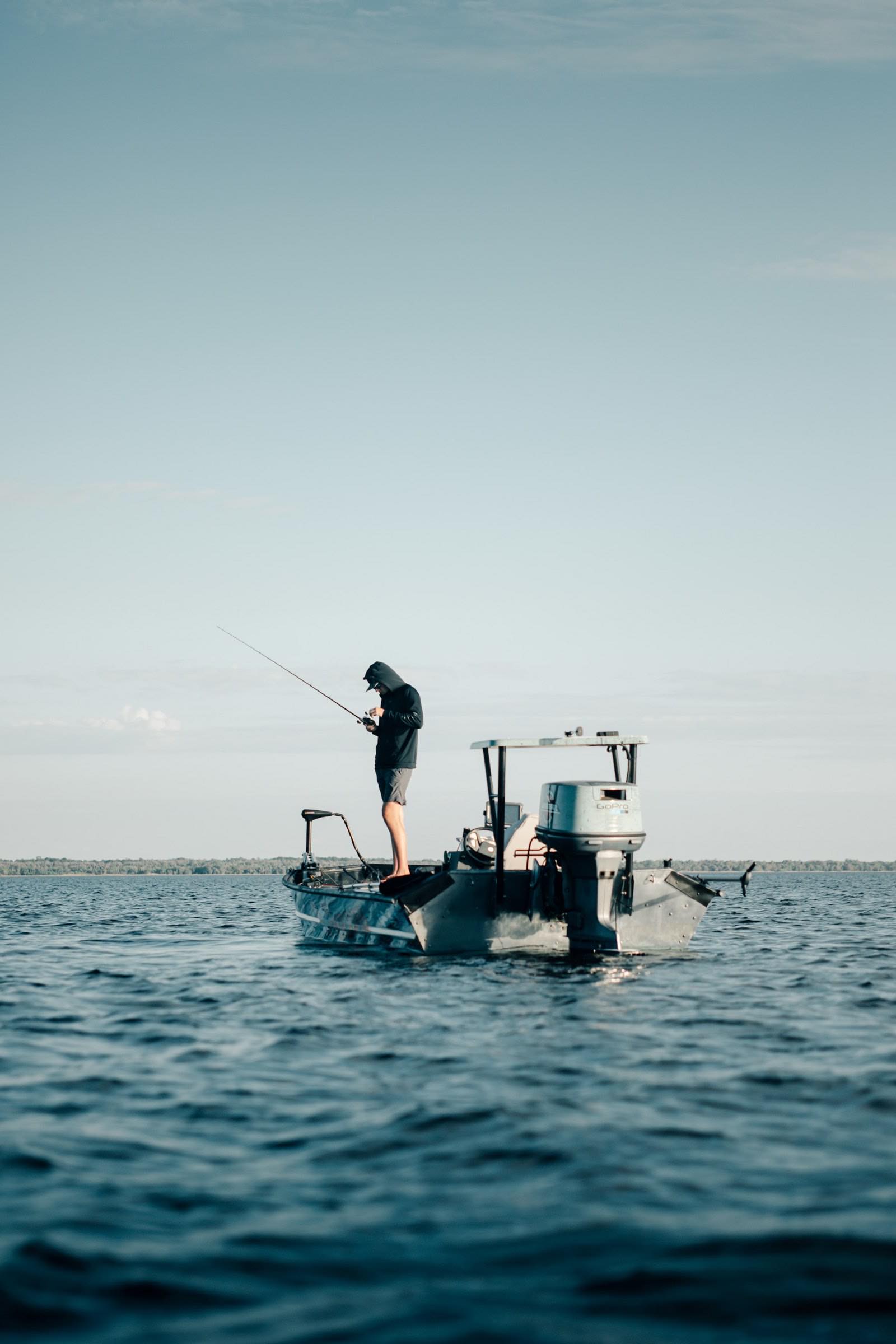 An angler working a rod from the deck of a boat on open water (stock photo)