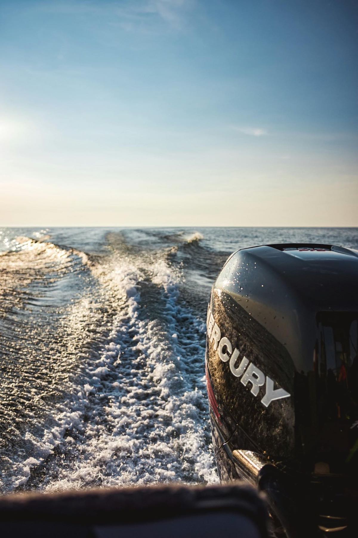 A Mercury outboard over a churning wake at golden hour (stock photo)